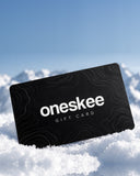 Black Oneskee gift card with topographic pattern standing in snow, with mountains behind